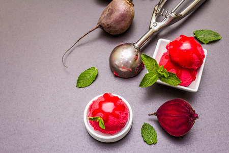 Beet ice cream, sorbet, gelato, sweet icing. Summer healthy refreshment dessert. Vegetarian (vegan) trendy food concept. With fresh vegetables and mint. Stone concrete background, copy spaceの写真素材