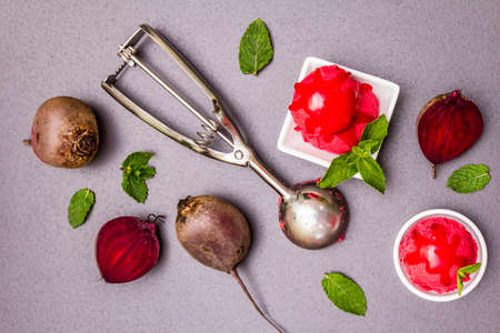 Beet ice cream, sorbet, gelato, sweet icing. Summer healthy refreshment dessert. Vegetarian (vegan) trendy food concept. With fresh vegetables and mint. Stone concrete background, top viewの写真素材