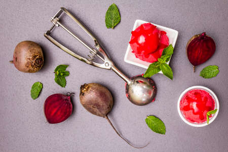 Beet ice cream, sorbet, gelato, sweet icing. Summer healthy refreshment dessert. Vegetarian (vegan) trendy food concept. With fresh vegetables and mint. Stone concrete background, top viewの写真素材
