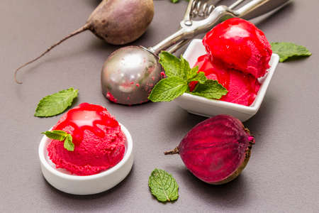 Beet ice cream, sorbet, gelato, sweet icing. Summer healthy refreshment dessert. Vegetarian (vegan) trendy food concept. With fresh vegetables and mint. Stone concrete background, close upの写真素材