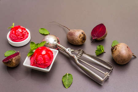 Beet ice cream, sorbet, gelato, sweet icing. Summer healthy refreshment dessert. Vegetarian (vegan) trendy food concept. With fresh vegetables and mint. Stone concrete background, copy spaceの写真素材