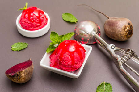 Beet ice cream, sorbet, gelato, sweet icing. Summer healthy refreshment dessert. Vegetarian (vegan) trendy food concept. With fresh vegetables and mint. Stone concrete background, close upの写真素材