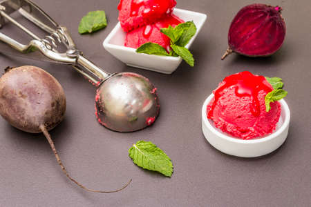 Beet ice cream, sorbet, gelato, sweet icing. Summer healthy refreshment dessert. Vegetarian (vegan) trendy food concept. With fresh vegetables and mint. Stone concrete background, close upの写真素材