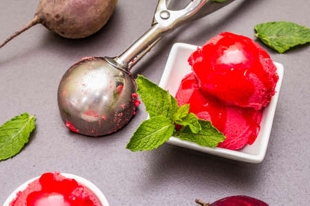 Beet ice cream, sorbet, gelato, sweet icing. Summer healthy refreshment dessert. Vegetarian (vegan) trendy food concept. With fresh vegetables and mint. Stone concrete background, close upの写真素材