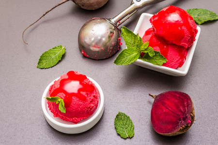 Beet ice cream, sorbet, gelato, sweet icing. Summer healthy refreshment dessert. Vegetarian (vegan) trendy food concept. With fresh vegetables and mint. Stone concrete background, close upの写真素材