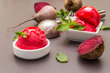 Beet ice cream, sorbet, gelato, sweet icing. Summer healthy refreshment dessert. Vegetarian (vegan) trendy food concept. With fresh vegetables and mint. Stone concrete background, close upの写真素材
