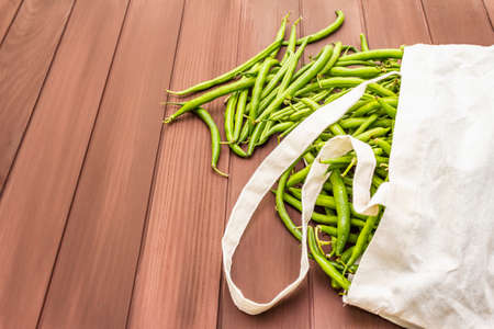 The cowpea (Vigna unguiculata). Fresh long beans in reusable shopping cotton bag. ECO trend to reduce disposable plastic. Wooden boards background, copy spaceの写真素材