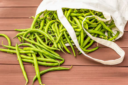 The cowpea (Vigna unguiculata). Fresh long beans in reusable shopping cotton bag. ECO trend to reduce disposable plastic. Wooden boards background, close upの写真素材