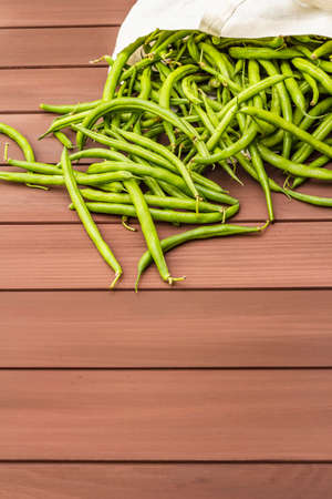 The cowpea (Vigna unguiculata). Fresh long beans in reusable shopping cotton bag. ECO trend to reduce disposable plastic. Wooden boards background, copy spaceの写真素材