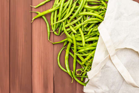 The cowpea (Vigna unguiculata). Fresh long beans in reusable shopping cotton bag. ECO trend to reduce disposable plastic. Wooden boards background, copy space, top viewの写真素材