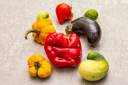 Trendy ugly organic vegetables. Assortment of fresh pepper, eggplant, cucumber, tomato, pumpkin. Cooking ugly food concept. Stone concrete background, close upの写真素材