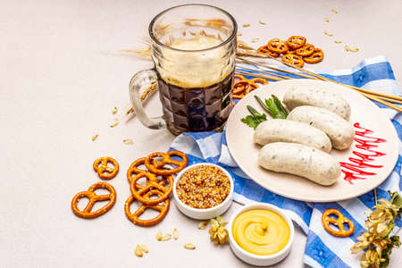Oktoberfest set. Dark beer, weisswurst, pretzels, mustard, spikelets of grain, hop. Traditional German cuisine, festival food. Mug, linen napkin, stone concrete background copy spaceの写真素材