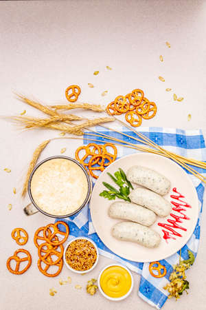 Oktoberfest set. Dark beer, weisswurst, pretzels, mustard, spikelets of grain, hop. Traditional German cuisine, festival food. Mug, linen napkin, stone concrete background copy space top viewの写真素材