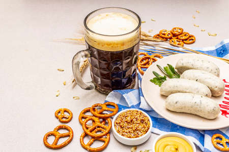 Oktoberfest set. Dark beer, weisswurst, pretzels, mustard, spikelets of grain, hop. Traditional German cuisine, festival food. Mug, linen napkin, stone concrete background copy space close upの写真素材