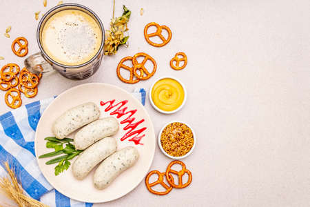 Oktoberfest set. Dark beer, weisswurst, pretzels, mustard, spikelets of grain, hop. Traditional German cuisine, festival food. Mug, linen napkin, stone concrete background copy space top viewの写真素材