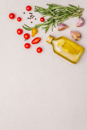 Cooking food background. Fresh rosemary, tomato cherry, garlic clove, olive oil, black pepper. Herbs and vegetables on light stone concrete background copy space top viewの写真素材