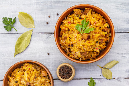 Stewed (braised) cabbage served on ethnic ceramic bowl. Traditional Polish Bigos with meat, aromatic...