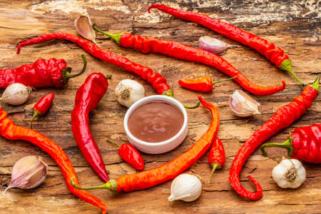 Traditional Thai sauce Sriracha with ingredients. Slightly dried red and orange chilli, garlic. In ceramic bowl, wooden bark backgroundの写真素材