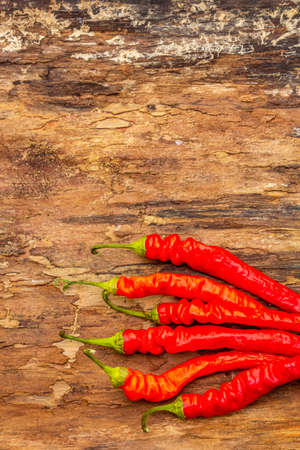 Red and orange chili pepper cooking food background. Traditional ingredients for preparation healthy vegan (vegetarian) meal. Wooden bark background, copy space, top viewの写真素材