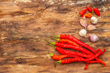 Red and orange chili pepper with garlic cooking food background. Traditional ingredients for preparation healthy vegan (vegetarian) meal. Wooden bark background, copy space, top viewの写真素材