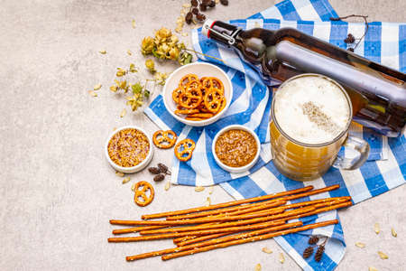 Oktoberfest set. Light beer, pretzels, mustard, sesame straw, hop. Traditional German cuisine, festival food. Bottles, linen napkin, stone concrete background, wooden backdrop copy space, top viewの写真素材