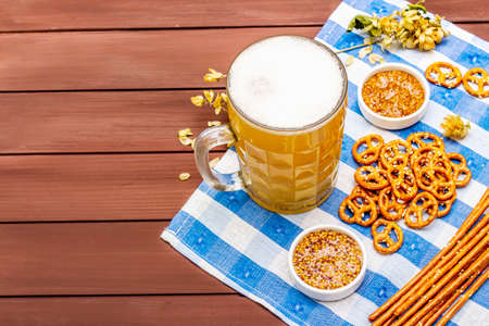 Oktoberfest set. Light beer, pretzels, mustard, sesame straw, hop. Traditional German cuisine, festival food. Bottles, linen napkin, wooden boards background, copy space, top viewの写真素材