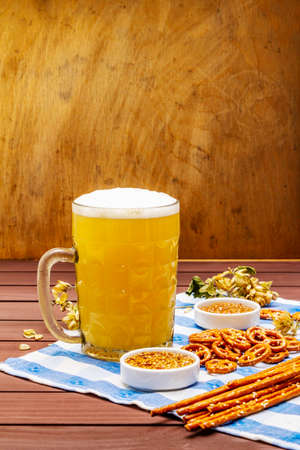 Oktoberfest set. Light beer, pretzels, mustard, sesame straw, hop. Traditional German cuisine, festival food. Bottles, linen napkin, wooden boards background, copy space, close upの写真素材