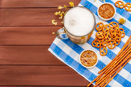 Oktoberfest set. Light beer, pretzels, mustard, sesame straw, hop. Traditional German cuisine, festival food. Bottles, linen napkin, wooden boards background, copy space, top viewの写真素材