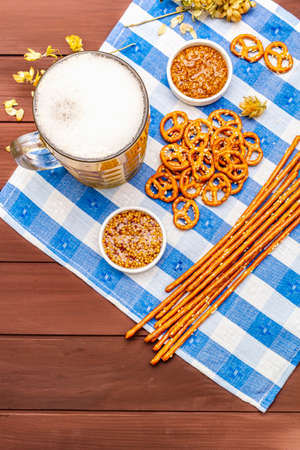 Oktoberfest set. Light beer, pretzels, mustard, sesame straw, hop. Traditional German cuisine, festival food. Bottles, linen napkin, wooden boards background, copy space, top viewの写真素材