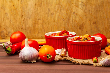 Marinated salad with pickled vegetables: eggplant, carrot, pepper, tomato, garlic. Healthy food concept, autumn harvest products recipe. Wooden boards background, copy spaceの写真素材