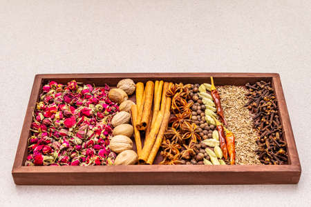 Ras el Hanout, exotic luxury spice with rose petals. Ingredients for preparation oriental spice mix in wooden box. An essential spice for any Moroccan dishes. Stone concrete background copy spaceの写真素材