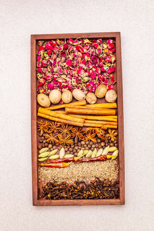 Ras el Hanout, exotic luxury spice with rose petals. Ingredients for preparation oriental spice mix in wooden box. An essential spice for any Moroccan dishes. Stone concrete background, top viewの写真素材