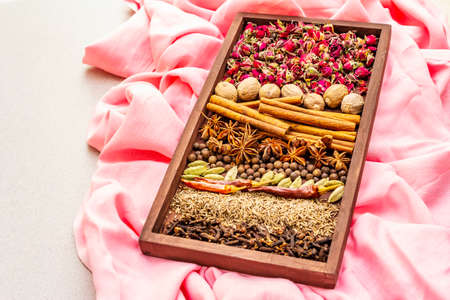 Ras el Hanout, exotic luxury spice. Ingredients for preparation oriental spice mix in wooden box. An essential spice for any Moroccan dishes. Stone background, pink cloth copy space close upの写真素材