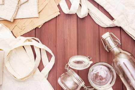 Assortment eco friendly packaging, zero waste, paper, glass and textile for free plastic shopping. Recycled materials. Bags, jars, box, bottle, packet on wooden boards background, copy space top viewの写真素材