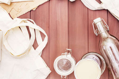 Assortment eco friendly packaging, zero waste, paper, glass and textile for free plastic shopping. Recycled materials. Bags, jars, box, bottle, packet on wooden boards background, copy space top viewの写真素材