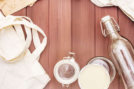 Assortment eco friendly packaging, zero waste, paper, glass and textile for free plastic shopping. Recycled materials. Bags, jars, box, bottle, packet on wooden boards background, copy space top viewの写真素材