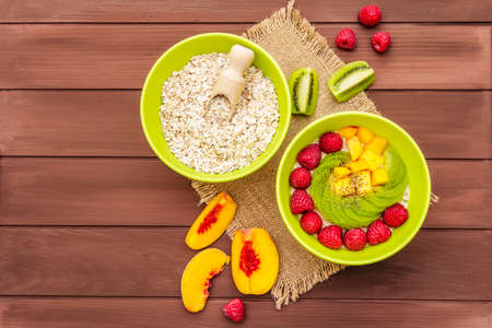 Oatmeal bowl with fresh berries and fruits. Healthy breakfast nutrition concept, vegetarian (vegan) food. Homemade vitamin eating, good mood. Wooden boards background, copy space, top viewの写真素材