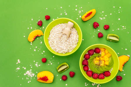 Oatmeal bowl with fresh berries and fruits. Healthy breakfast nutrition concept, vegetarian (vegan) food. Homemade vitamin eating, good mood. Bright green background, top viewの写真素材