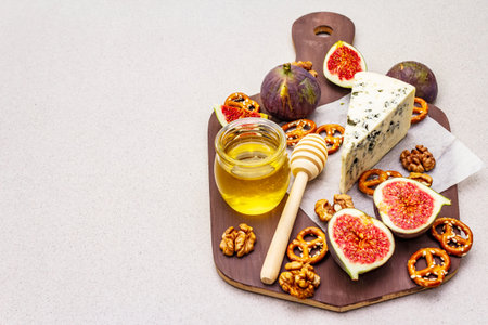 Cheese platter (board) with blue cheese, honey, walnuts, figs, pretzels. Traditional healthy...
