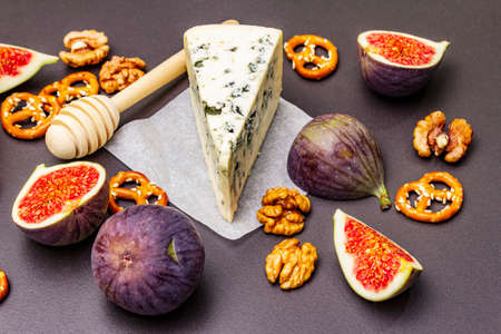 Cheese appetizer selection or wine snack set. Blue cheese, figs, honey, walnuts, pretzels. Traditional healthy antipasti on black stone concrete background, close upの写真素材