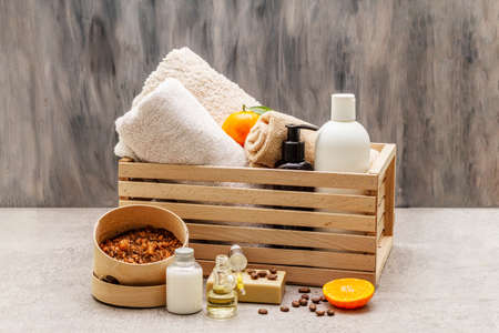 Coffee and tangerine spa concept. Towels, oil, scrub, soap, lotion. Natural ingredient, wooden box. Stone concrete background, copy space, close upの写真素材