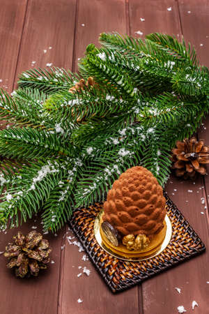 Festive dessert in the shape of a Christmas fir cone. New Year sweet treat concept. Wooden boards backgroundの写真素材
