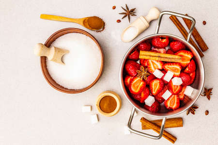 Strawberry jam. Ingredients for making homemade sweet dessert. Home preservation concept. Fresh berries, sugar, cinnamon, star anise. Stone concrete background, top view, close upの写真素材