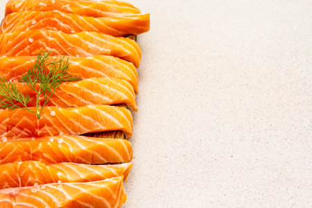 Slices of fresh salmon fish. Raw ingredient for cooking healthy seafood. Concept omega 3 containing food. Vintage wooden cutting board, stone concrete background, copy space, top viewの写真素材