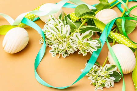 Easter decoration background. Eggs, ribbons, fresh flowers and leaves. Light matte beige backdrop, close upの写真素材