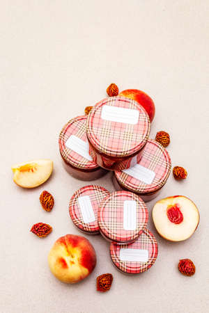 White peach jam, confiture, chutney in a glass jar. Homemade preservation concept. With fresh fruits, dry seeds on stone concrete background, copy space, top viewの写真素材