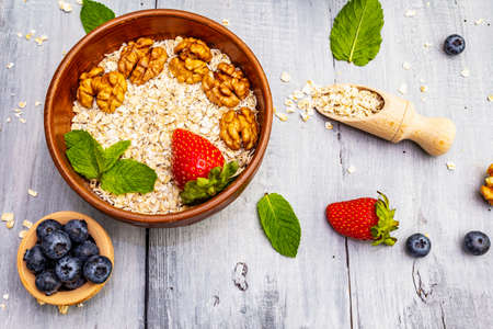 Healthy breakfast vegetarian (vegan) concept. Oatmeal with fresh berries, strawberry, walnuts and...