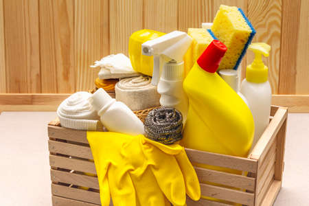 House cleaning product in wooden box. Spray, bottle, gloves, dishwashing sponge, scraper, gel air freshener. Stone concrete background, close upの写真素材