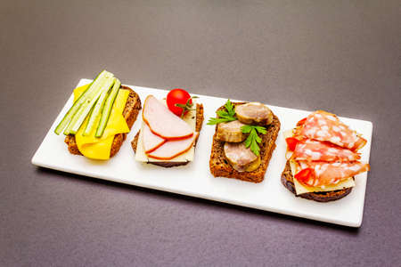 Assorted sandwiches with different fillings, meats, cheese and vegetables. Fresh snack on stone background, copy spaceの写真素材
