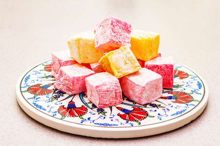 Eastern sweets. Traditional Turkish delight Rahat lukum with a rose and citrus on ceramics with...